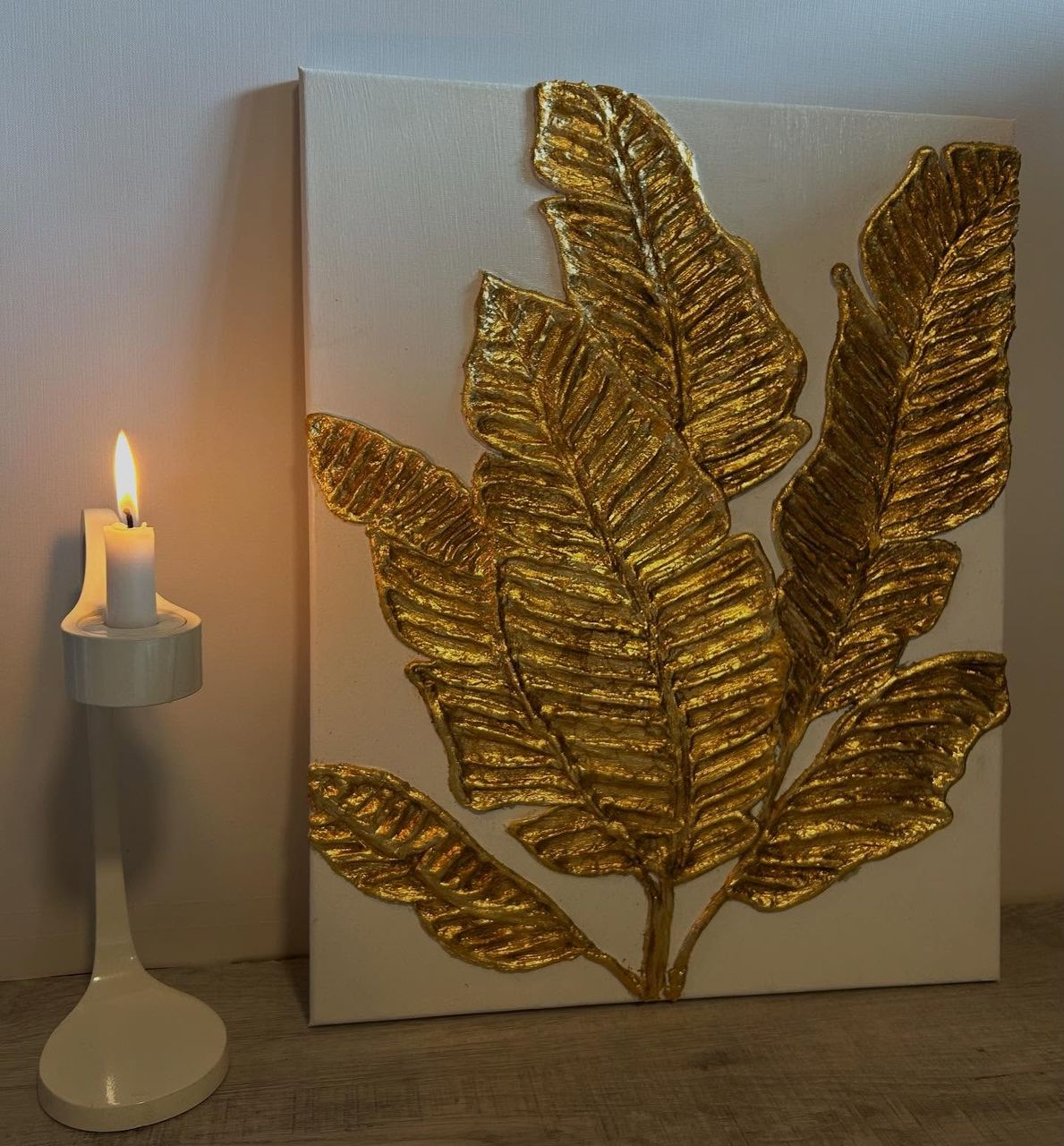 Goldene Blätter in Relief auf weißer Leinwand